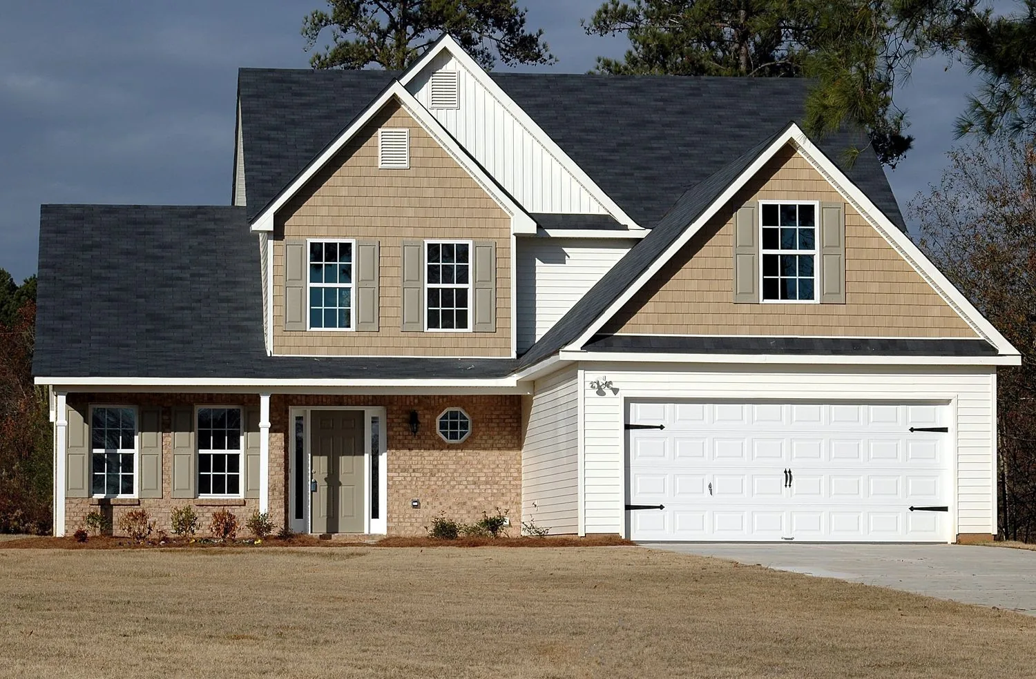 Two-story home with a white two-car garage door and carriage hardware